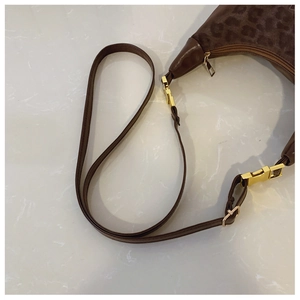 Close-up of leopard print fabric and dark brown leather with gold metal buckle detail