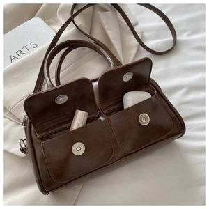 Detail of dark brown leather Boston bag with two front pockets for lipstick and earphones