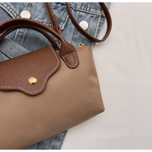 Close-up of contrast stitching and khaki nylon texture on leather flap handbag
