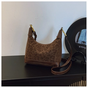 Detail of leopard print underarm bag with gold metal buckle and brown leather strap