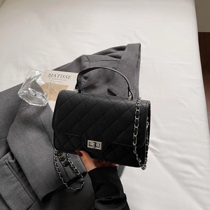 Klassische schwarze gesteppte Umhängetasche aus Leder mit Silberbeschlägen auf Bett