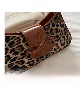 Macro view of leopard print bag zipper detail with brown patent leather bow decoration