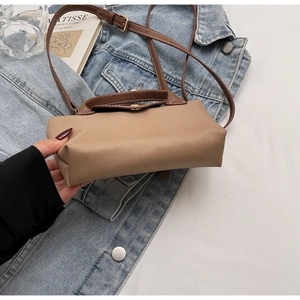 Detail of a contrast color crossbody bag with leather flap and adjustable strap