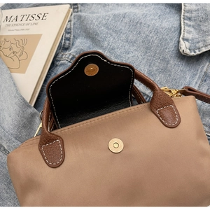 Detail of magnetic snap closure on a contrast color nylon handbag with leather handle