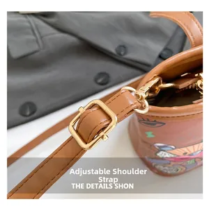 Détails de la bandoulière réglable en cuir et des boucles dorées du sac seau marron