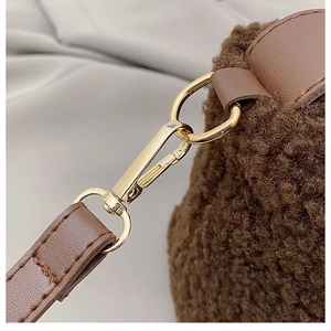 Detailansicht der braunen Tasche aus Lammfellimitat mit Lederriemen und Goldverschluss