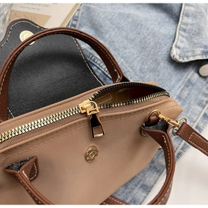 Detail of tan canvas handbag with synthetic leather trim and gold hardware numbered buckle