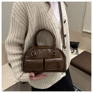Detail view of a vintage dark brown Boston bag with dual front pockets and glossy finish