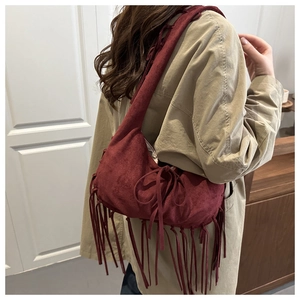 Détail d'un sac à bandoulière en daim bordeaux avec de longues franges et un nœud