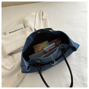 Interior detail of large denim tote bag showing magnetic buckle and spacious storage