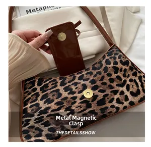 Close-up of leopard print bag showing the metal magnetic clasp and glossy leather lining