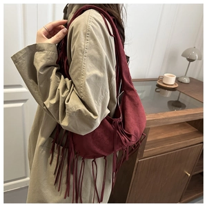 Vue latérale d'un sac cabas rétro bordeaux en daim avec franges sur un mannequin