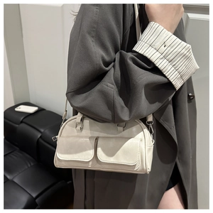Close-up of creamy white PU leather handbag featuring dual front flap pockets and silver hardware
