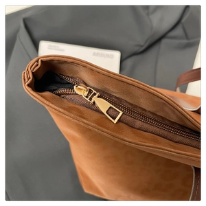 Detail of golden metal zipper and leopard print texture on a brown suede tote bag