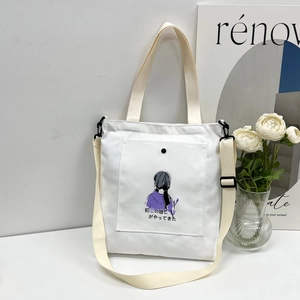 Detail of white canvas tote bag featuring floral art, snap button and adjustable strap