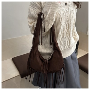 Détail d'un sac porté épaule en daim marron foncé avec de longues franges style bohème