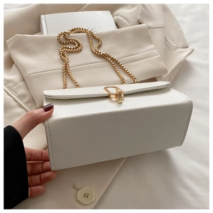 Detail of white leather mini bag with gold chain strap and elegant metallic buckle lock