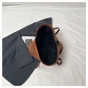 Macro shot of large brown suede tote bag with black lining and thin handles on a blazer
