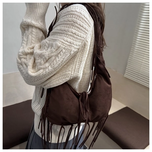 Détail du sac à bandoulière en daim marron foncé avec franges bohèmes et forme demi-lune