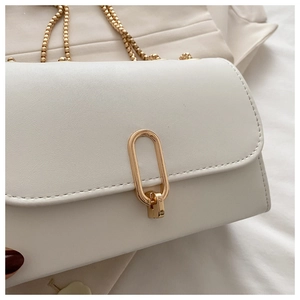 Detail of white leather shoulder bag featuring golden oval lock and beaded chain strap