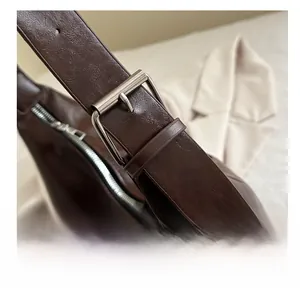 Détail de la bandoulière en cuir marron foncé avec boucle métallique argentée réglable