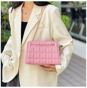 Macro detail of pink quilted faux leather texture with elegant gold chain strap