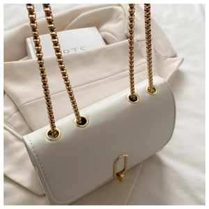 Detail of off-white leather flap bag with gold bead chain strap and U-shaped metal buckle