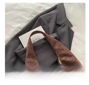 Close-up of leopard print hobo bag in brown suede fabric on a grey blazer background