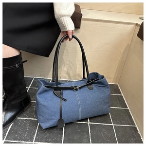Dettaglio borsa tote in denim blu con cuciture a contrasto e manici in pelle