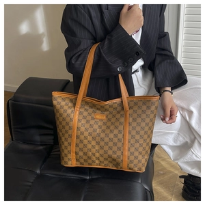 Detail of the high-capacity monogram tote bag with brown leather trim in a commute scene