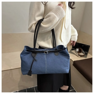 Borsa tote in denim blu con tracolle marroni indossata da una modella in interni moderni