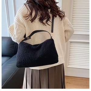 Detail einer flauschigen schwarzen Lammfell-Handtasche mit Lederriemen und Gold-Hardware