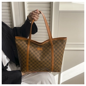 Macro shot of large tote bag featuring brown checkered pattern and leather trim details
