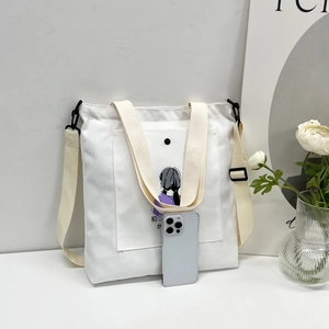 Detail of white canvas tote with adjustable strap and casual cartoon illustration