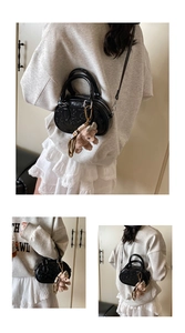 Détail d'un sac à main noir brillant avec motif en relief et breloque ours en peluche