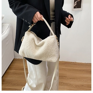 Detailaufnahme einer weißen Plüsch-Tragetasche mit Ledergriffen an einem weiblichen Model