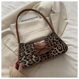 Detail of leopard print faux fur shoulder bag with brown leather trim and bow accent