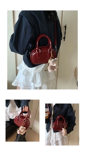 Détail d'un mini sac à main bordeaux brillant avec motifs gaufrés et ours en peluche