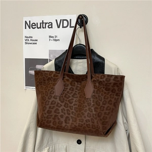 Retro leopard print tote bag with long leather straps shown against a stylish studio backdrop