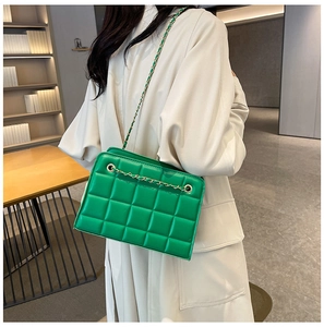 Detail of green quilted leather texture with gold chain strap on a chic shoulder bag