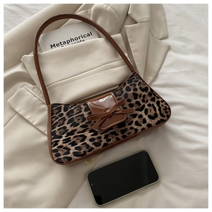 Detail of leopard print underarm bag with brown leather bow and phone for size reference