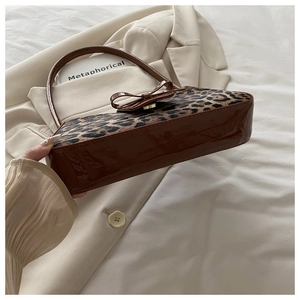 Detail of leopard print baguette bag with leather bow and golden magnetic buckle