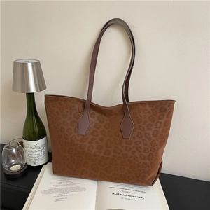 Retro leopard print tote bag with long shoulder straps placed on an open book