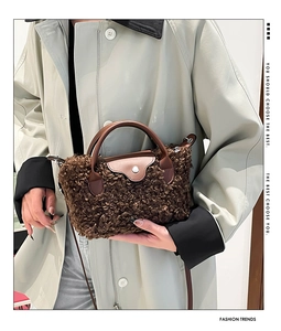 Detailed close-up of brown plush faux fur handbag with leather handle and snap closure