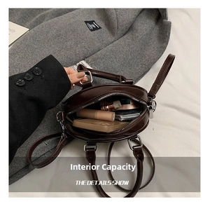 Capacité interne du sac rond marron foncé montrant l'espace pour téléphone et rouge