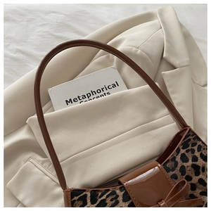 Detail of leopard print shoulder bag with bow decor on cream suit blazer