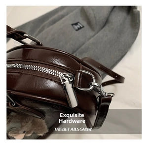 Détail du sac à main marron foncé en similicuir avec ferrures argentées et breloque peluche