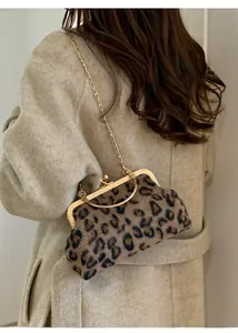 Detail of leopard print kiss-lock bag with gold chain and handle on a beige coat