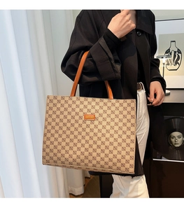 Close-up of a large tote bag with brown geometric patterns and orange leather straps