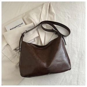 Détail du sac cabas rétro marron foncé avec large bandoulière sur tissu blanc
